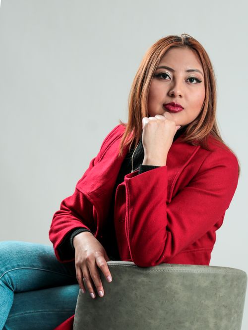 Free Stylish woman wearing red coat and jeans sitting thoughtfully, exuding fashion and confidence. Stock Photo