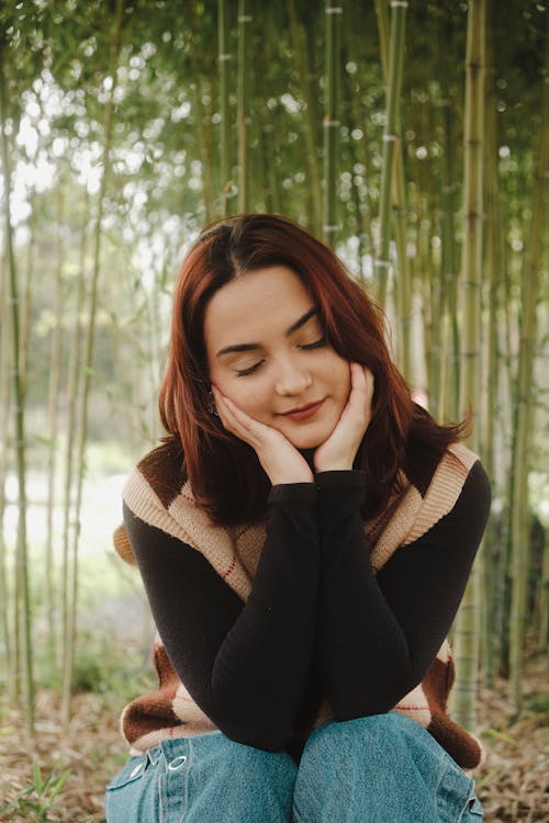 A woman sitting in front of bamboo trees