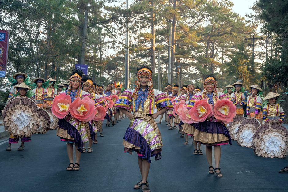 Traditional dancers in colorful costumes parade through Baguio City during a vibrant festival celebration.