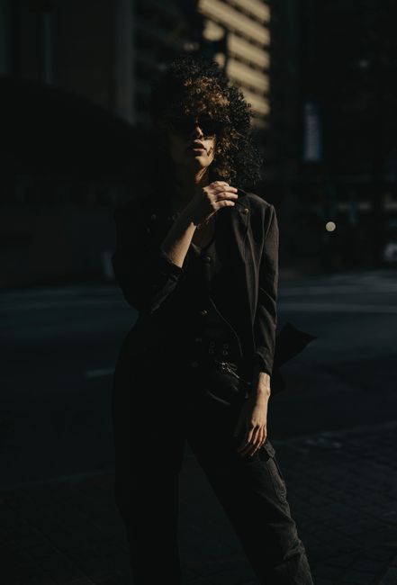 Stylish woman in black attire posing on city street in Atlanta, captured during golden hour.