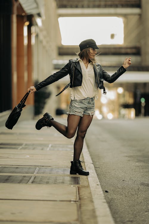 Young Woman in Trendy Clothing Posing on a Sidewalk in City 