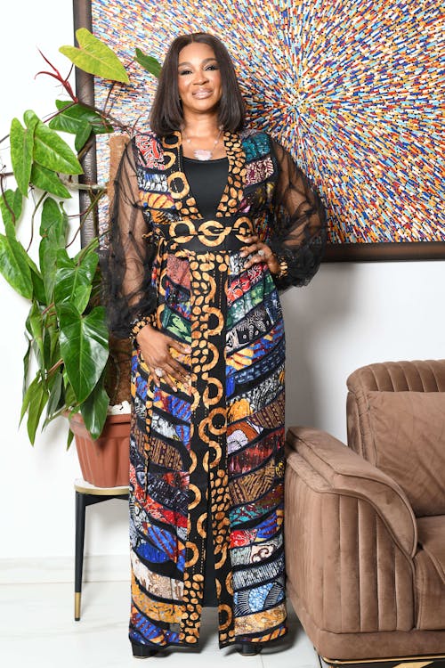 A woman in a long dress and a colorful african print jacket
