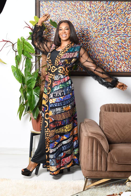 A Smiling Woman Posing in a Patterned Gown 