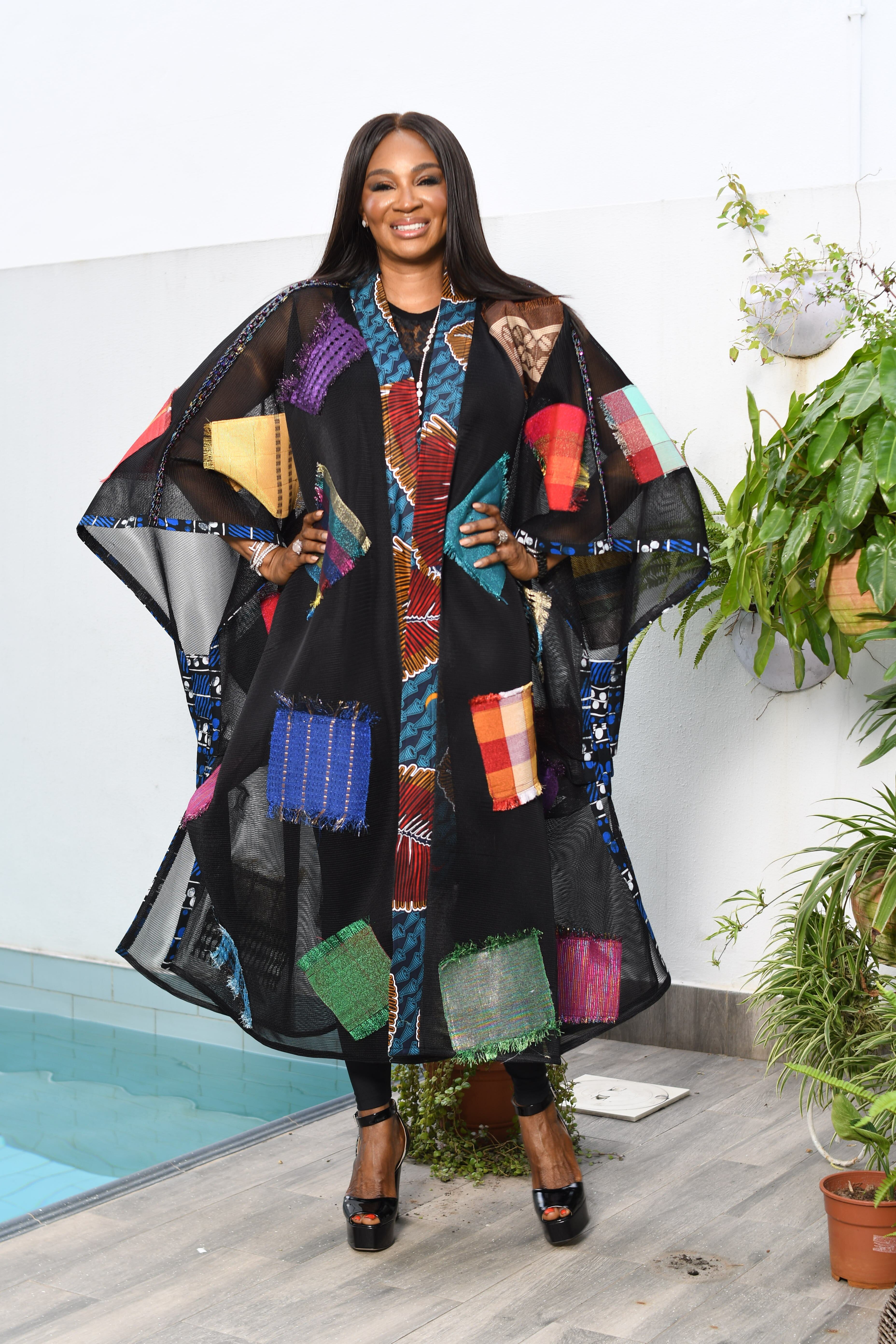 Stylish woman posing in a vibrant patchwork dress beside a pool.