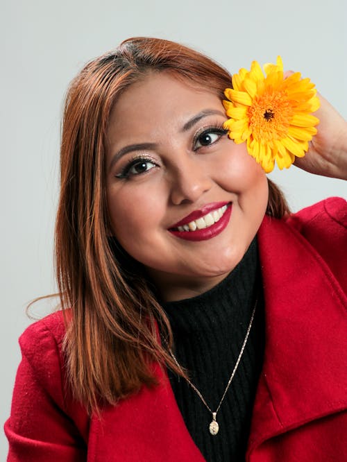 Photo of a Smiling Woman Holding a Yellow Flower 