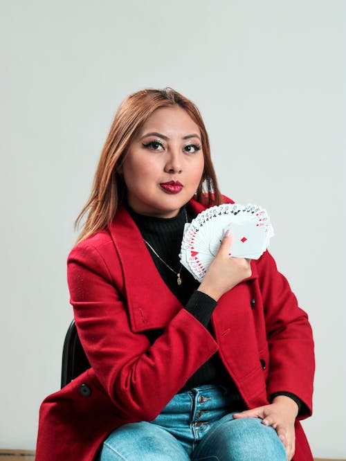 A woman in red jacket holding a playing card