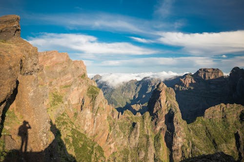 A person standing on top of a mountain with the mountains in the background