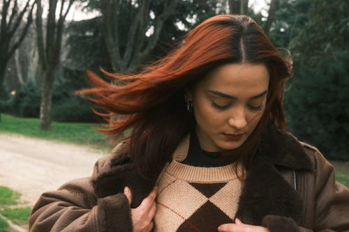 A woman with red hair wearing a sweater and jacket
