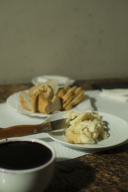 Fotomural Mesa acogedora con pan, queso y vino en una habitación cálida y con poca luz.