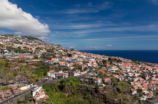 A scenic aerial view of Funchal, Madeira with charming red-roofed houses under a bright blue sky.
