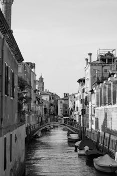 Classic Venice canal with moored boats and historic architecture in monochrome.