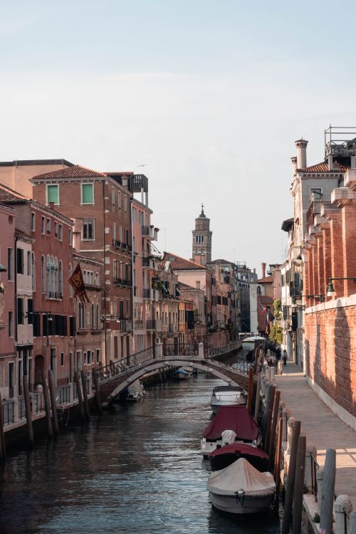 Free Picturesque canal in Venice featuring moored boats and historic buildings under a clear sky. Stock Photo
