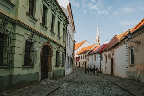 A cobblestone street with people walking down it