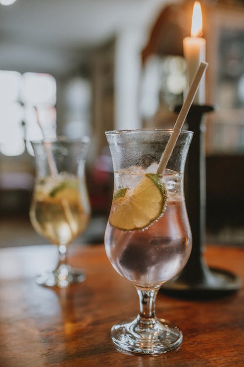 Two glasses of drinks with ice and a lime