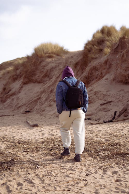 Foto profissional grátis de andando, areia, casaco com capuz
