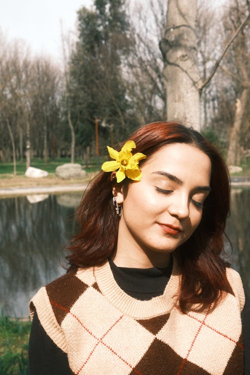 A woman with a flower in her hair standing near a pond