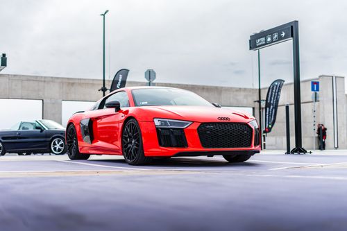 Free Dynamic shot of a red Audi R8 parked in an urban environment, showcasing sleek design and luxury. Stock Photo