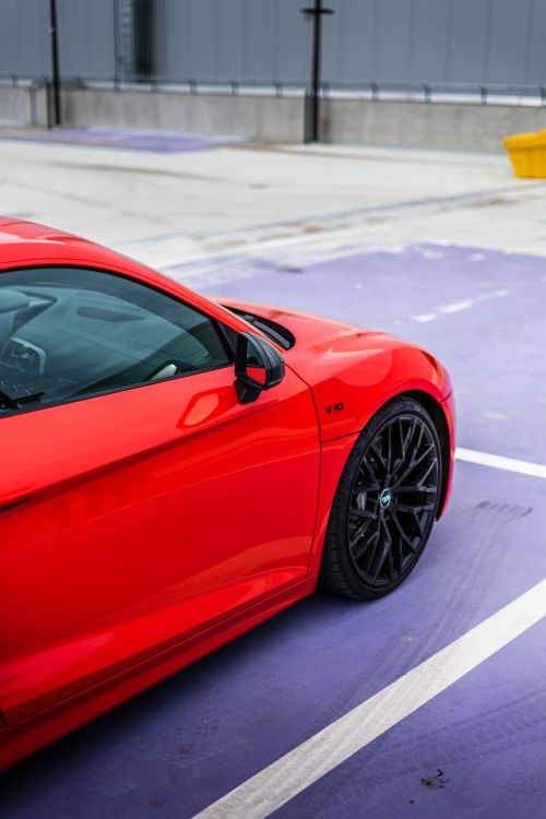 Free A luxurious red sports car parked in an urban setting, showcasing sleek design and vibrant color. Stock Photo