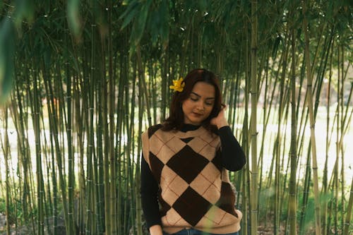 A woman in a sweater and jeans standing in front of bamboo trees