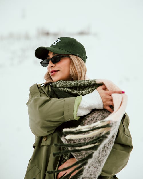 A woman in a green hat and scarf is standing in the snow