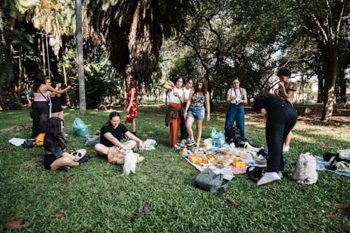 A group of people sitting on the grass with food