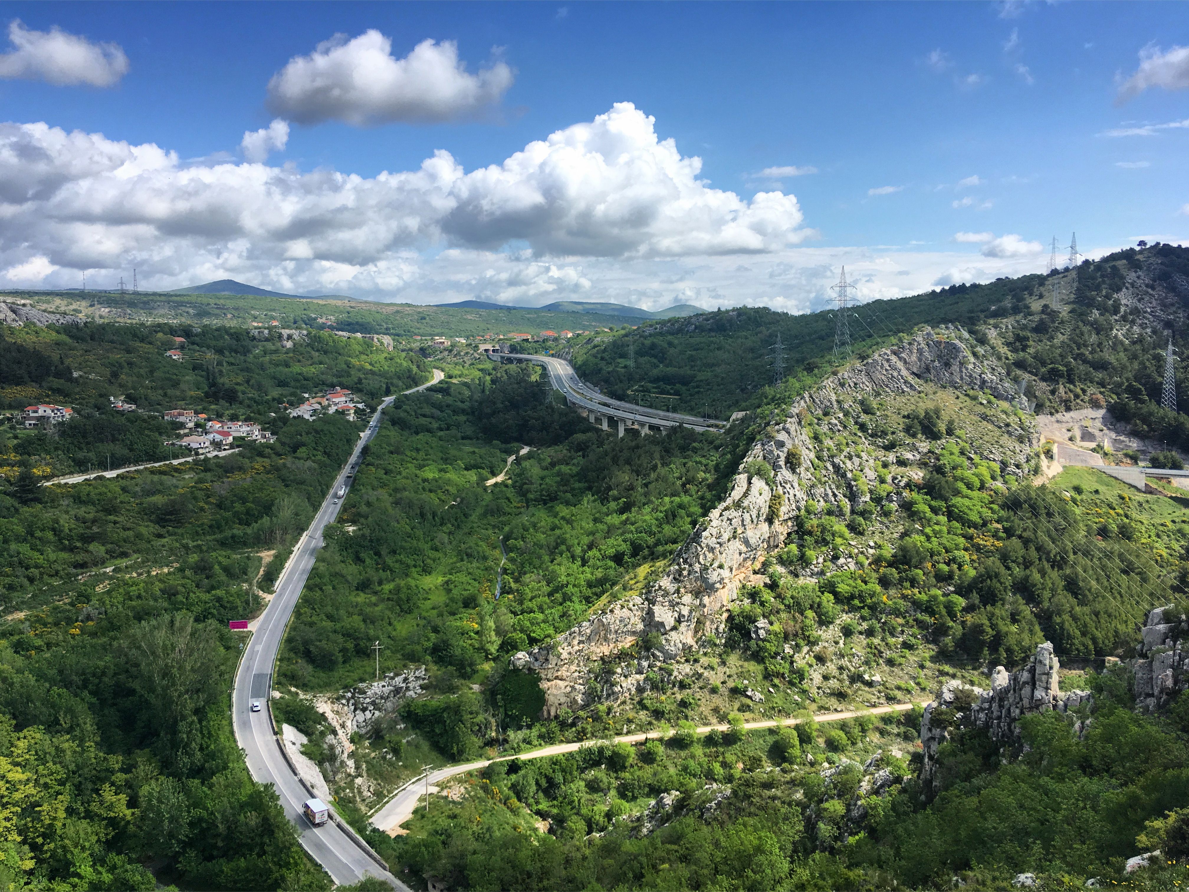 A breathtaking aerial view of Klis Fortress landscape with green forests and winding roads in Croatia.
