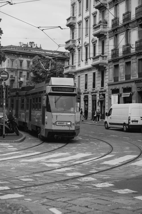 A black and white photo of a tram on a street