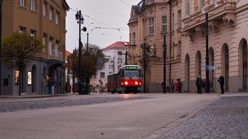A red and white train is traveling down a street
