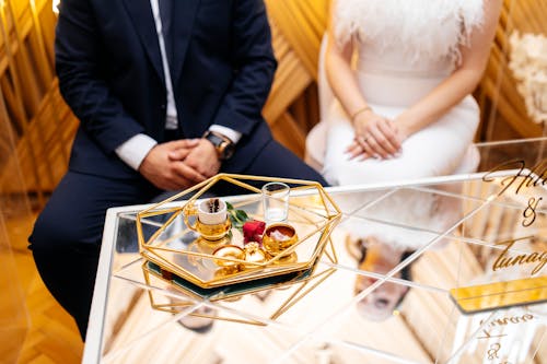 A couple sitting on a gold tray with a wedding ring