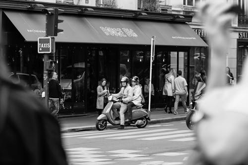 A black and white photo of a man on a scooter