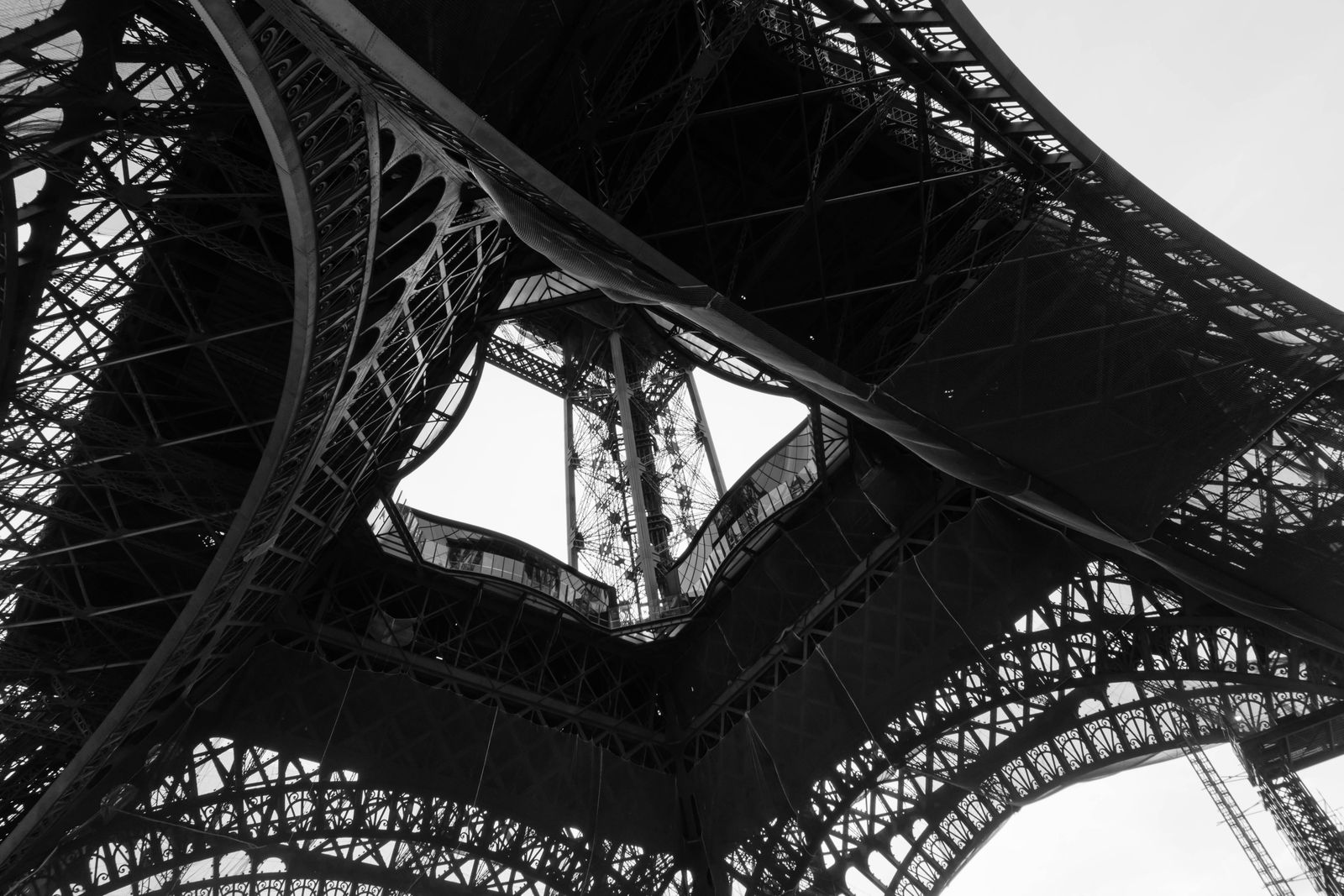 Vue rapprochée des poutrelles métalliques de la tour Eiffel et de leurs rivets, lumière chaude de fin de journée