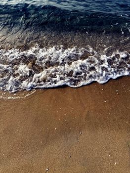 A peaceful view of clear waves gently washing onto the sandy shoreline at the beach.