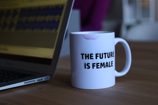 A white mug with 'The Future Is Female' beside a laptop, symbolizing empowerment.