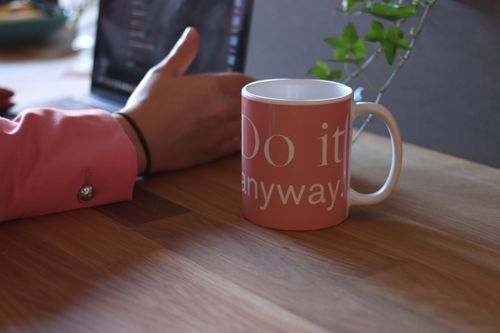 Free A cozy workspace featuring a motivational mug and a person using a laptop, perfect for productivity. Stock Photo