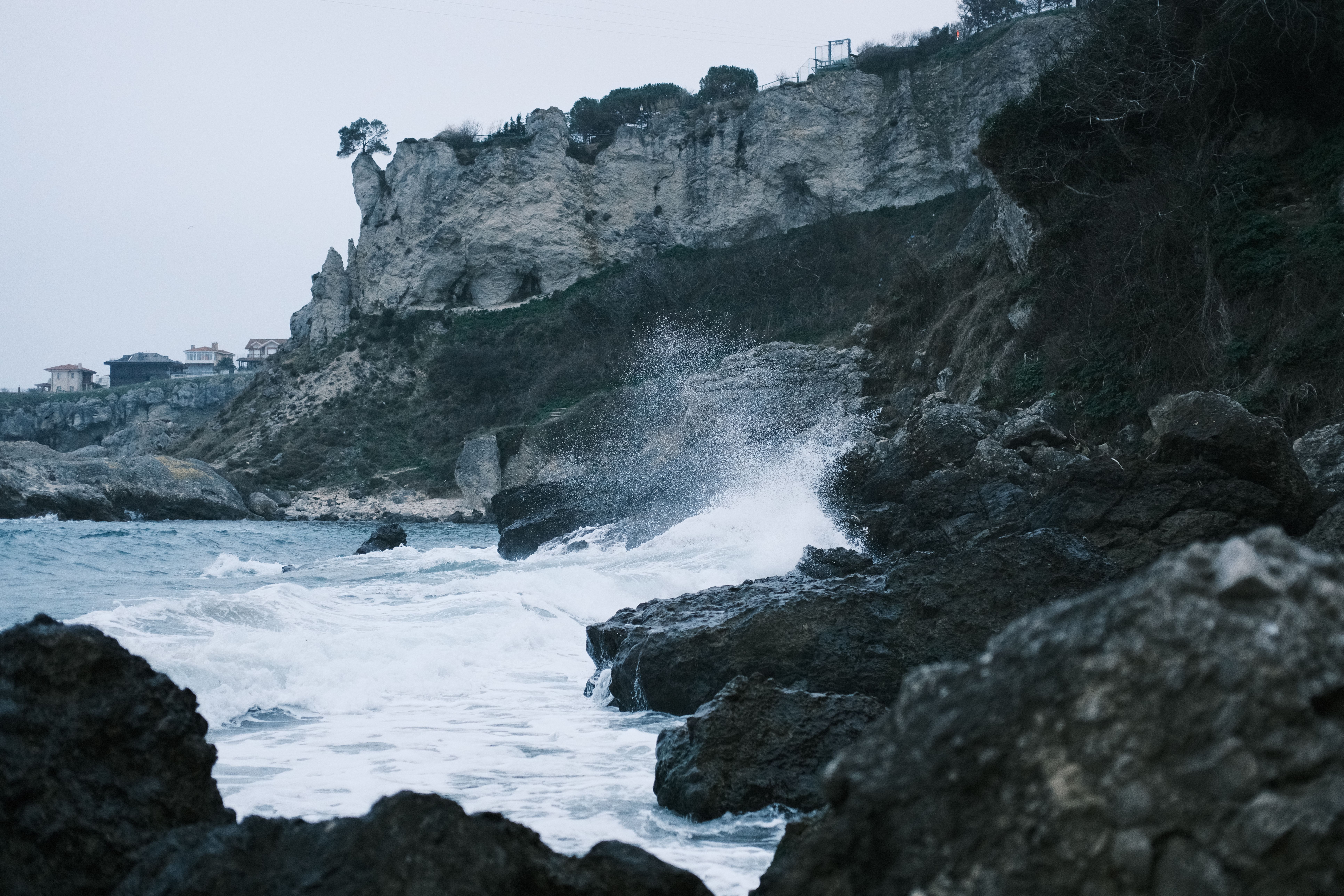 Dynamic coastal scene featuring cliffs, rocks, and crashing waves against a moody backdrop.