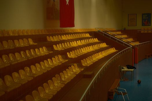 Empty sports hall with yellow seats and Turkish flag, ideal for events.