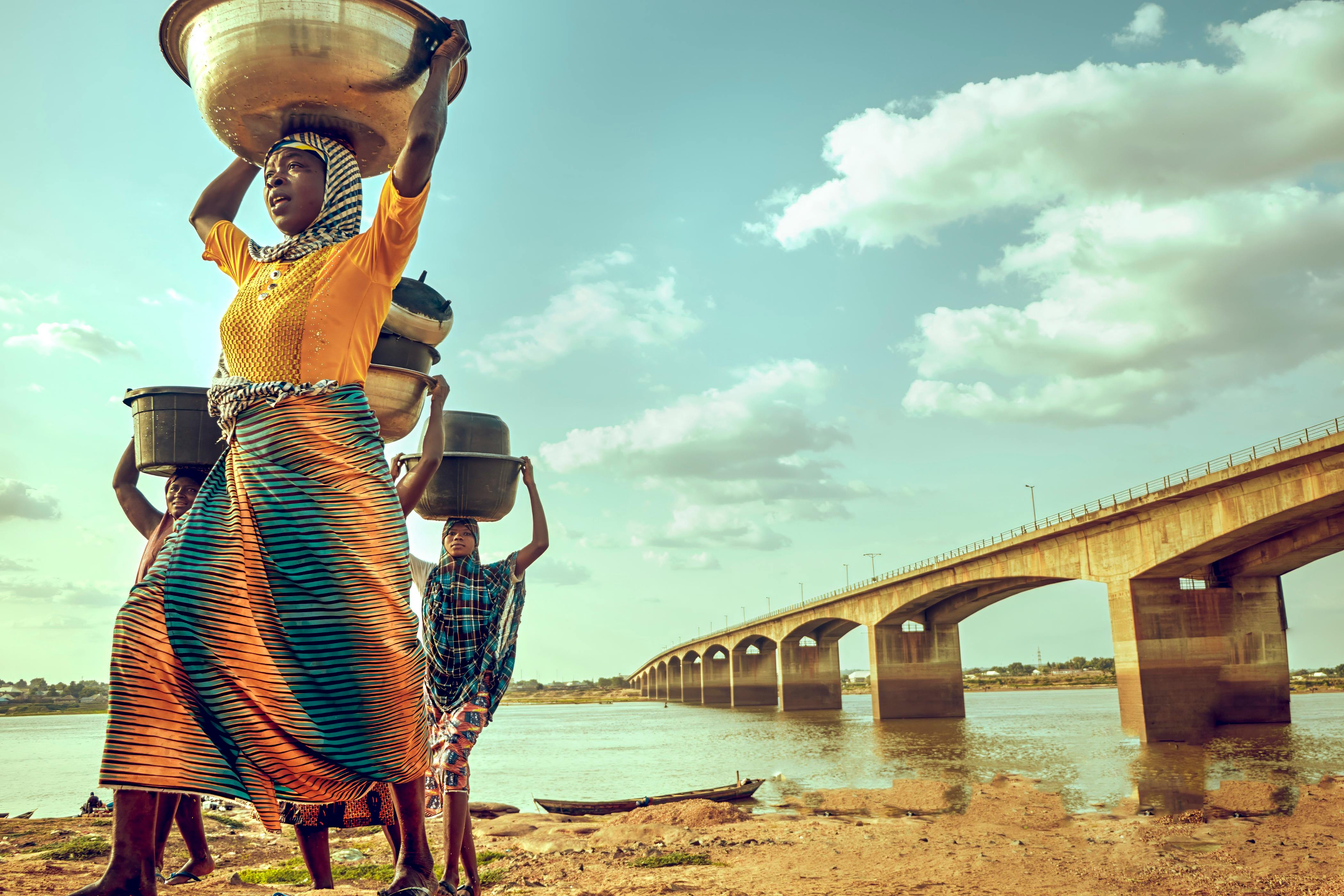 Women carrying goods on their heads by the river near Makurdi Bridge, Nigeria.