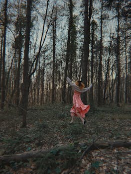 Woman in elegant dress dancing freely in a mystical Istanbul forest.