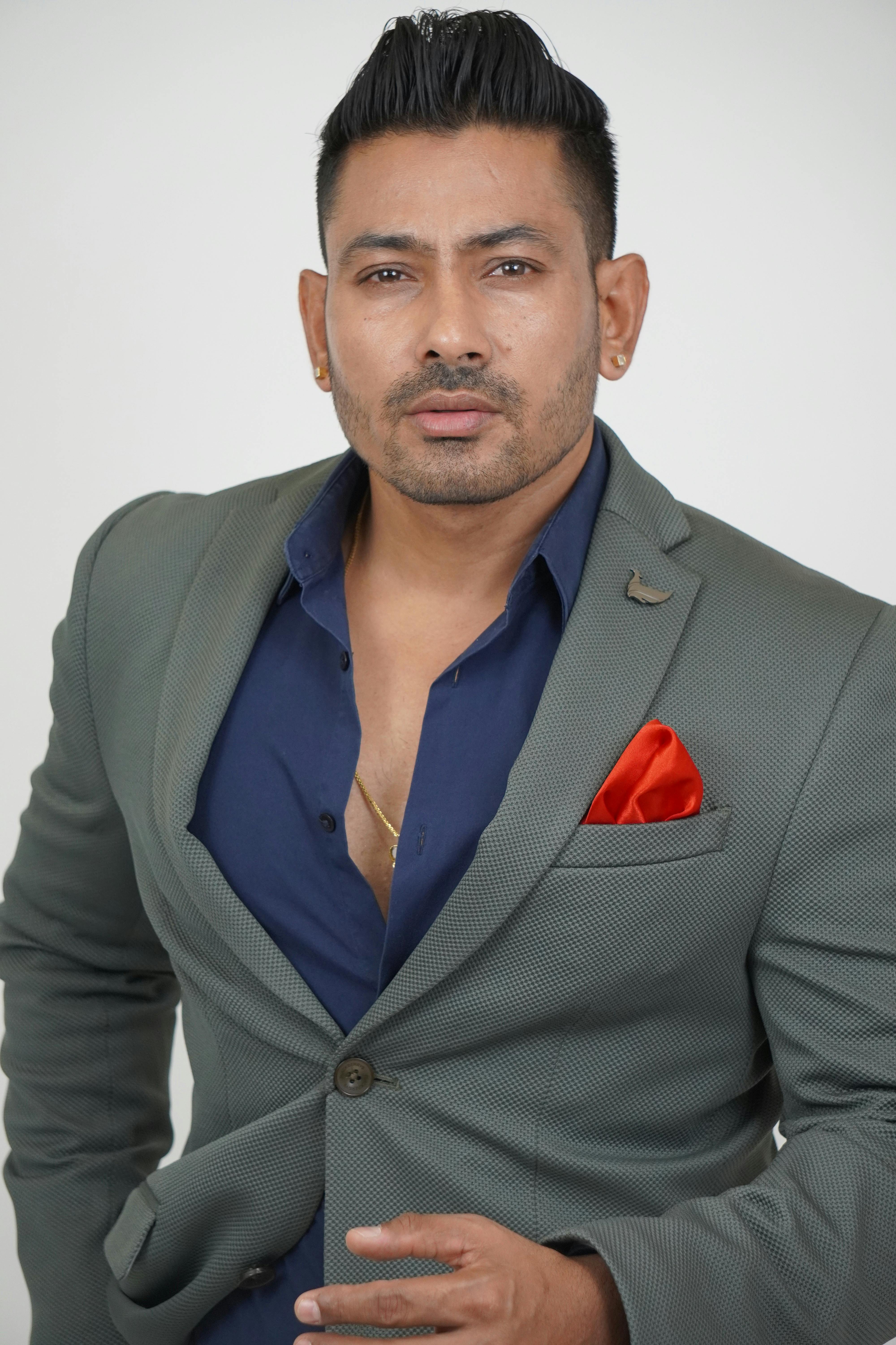 Stylish portrait of a man in a gray suit with a red pocket square on a white background.