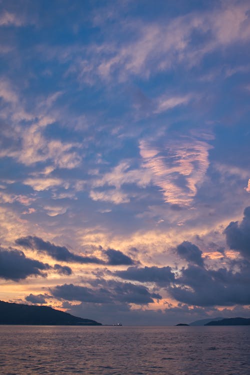 A sunset over the ocean with clouds in the sky