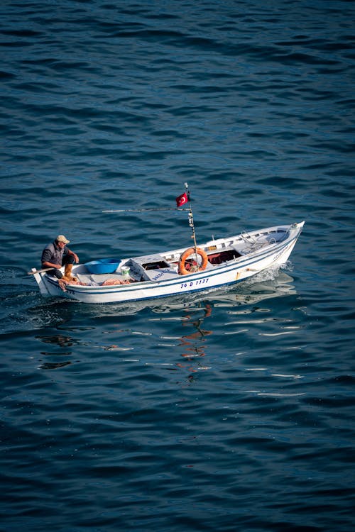 A man is sitting in a small boat in the ocean