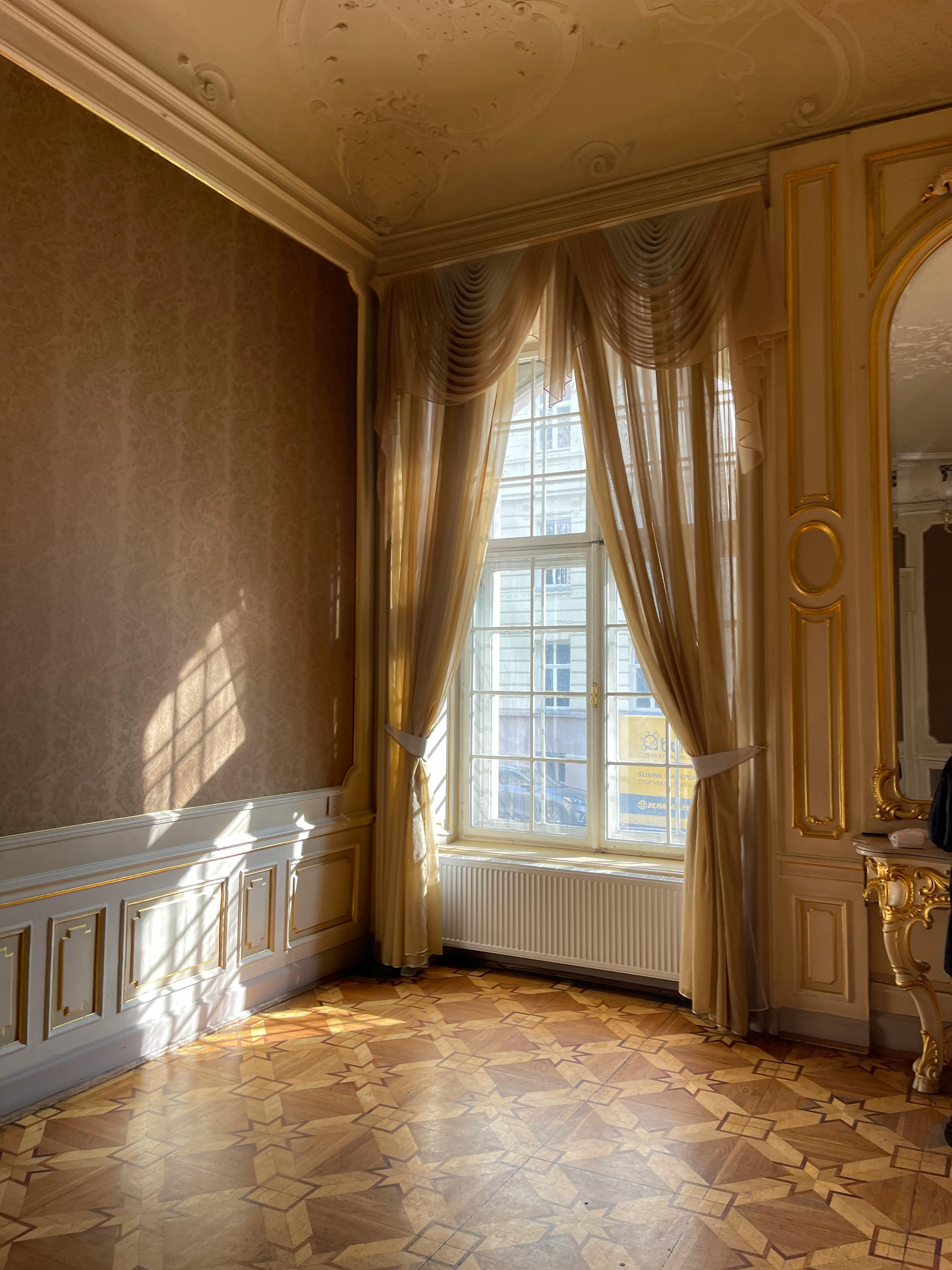 Free Sunlight streaming through a window in a richly decorated palace interior with vintage curtains. Stock Photo