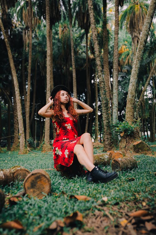 A woman in a red dress sitting in the middle of a forest