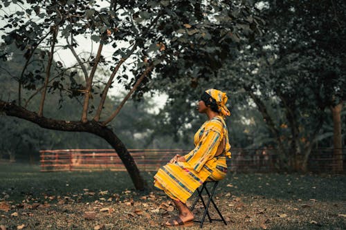 A person sitting on a chair under a tree