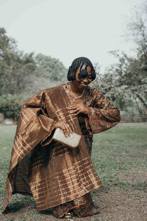 A woman in a brown and gold outfit holding a purse