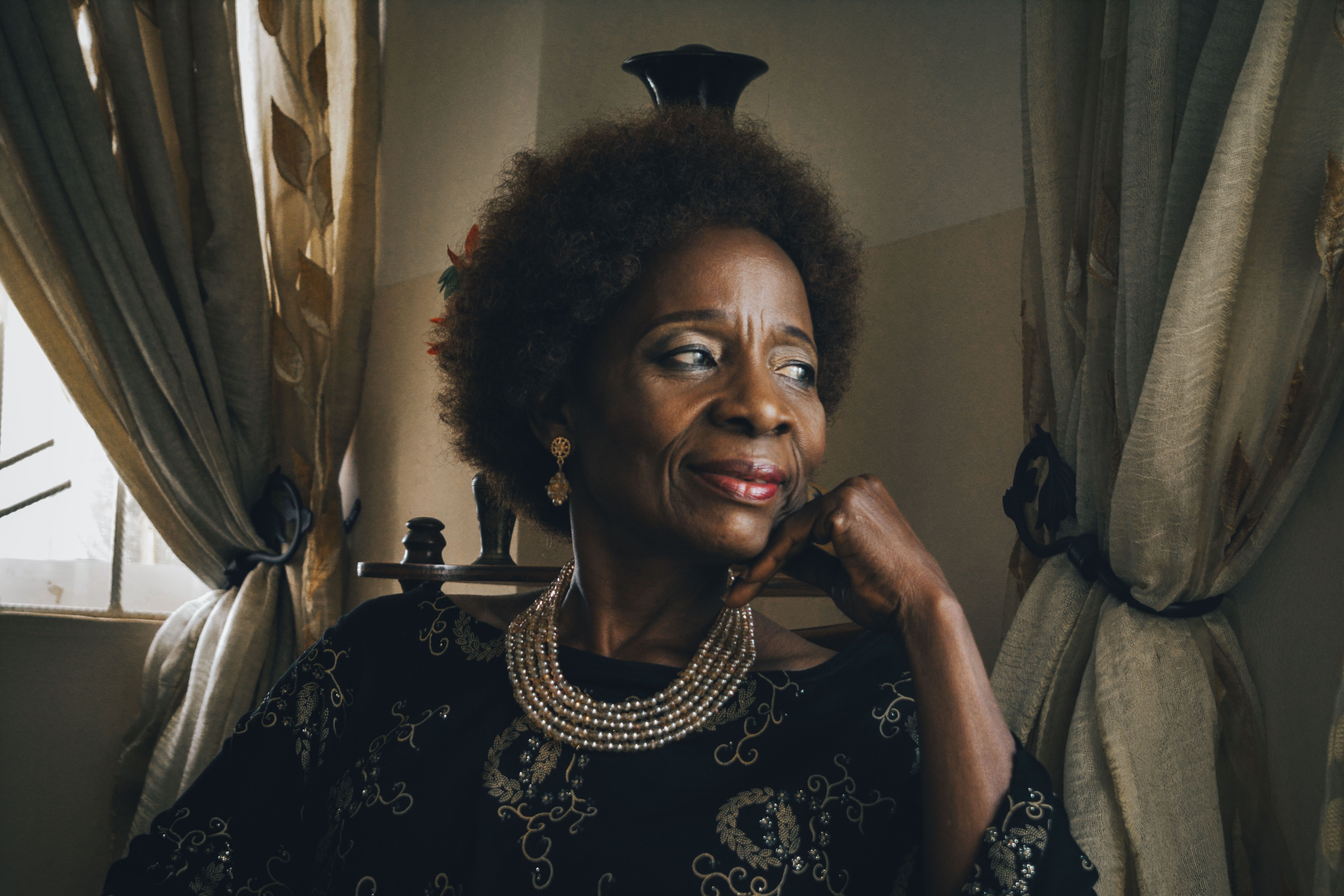 Portrait of an older woman with curly hair and jewelry, reflecting elegance and wisdom.