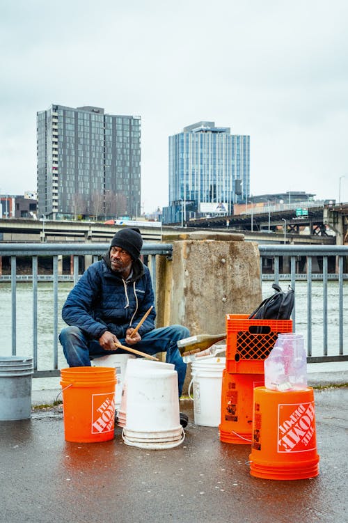 A man sitting on the ground next to buckets