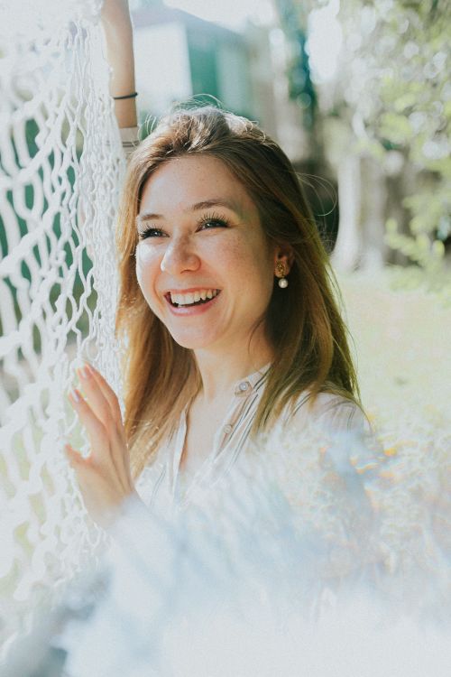Free A joyful woman with brown hair smiling in sunlight, outdoors with a net. Stock Photo