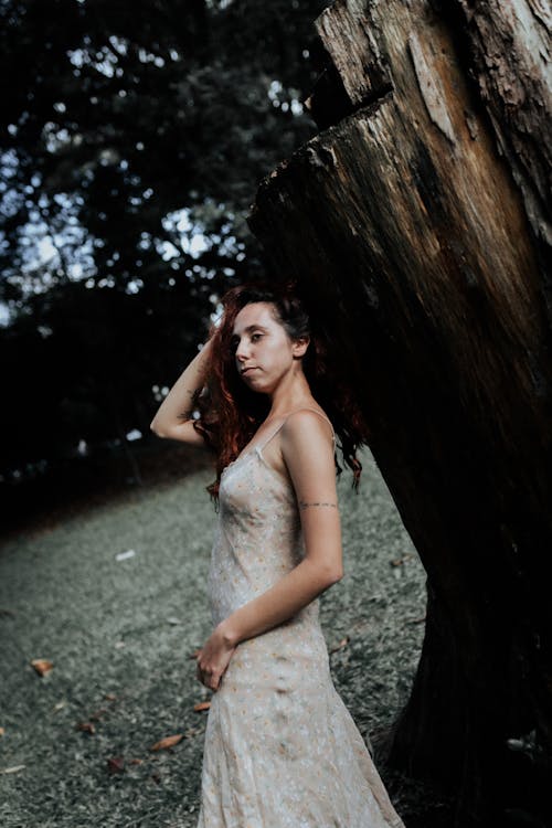 A woman in a wedding dress standing next to a tree