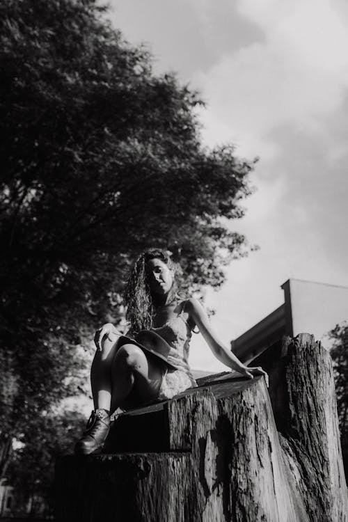 A woman sitting on top of a tree stump